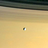 Cassini image of the moon Dione orbiting above Saturn's rings