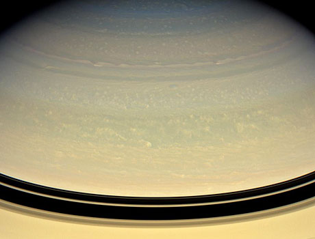 Image of the planet Saturn captured by NASA's Cassini spacecraft showing horizontal bands and puffy swirls in the atmosphere