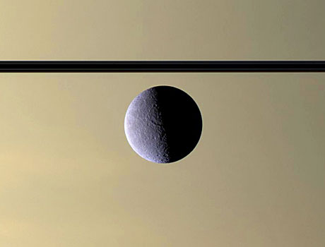 Image of Saturn's icy moon Rhea floating above the planet's murky atmosphere