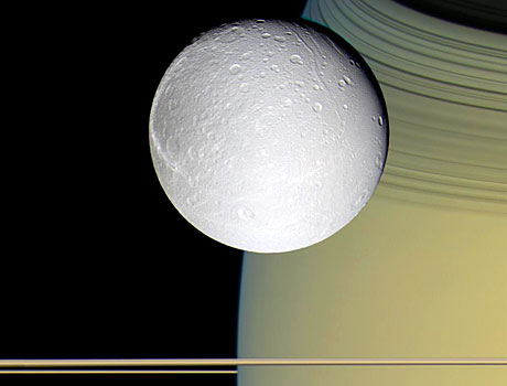 Image of Saturn's moon Dione orbiting above the giant planet