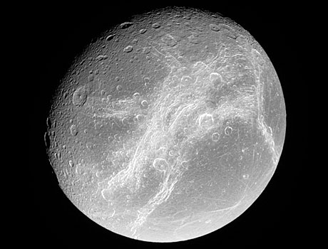 Image of Saturn's moon Dione taken by NASA's Cassini spacecraft, showing the moon's heavily cratered surface and bright, wispy features